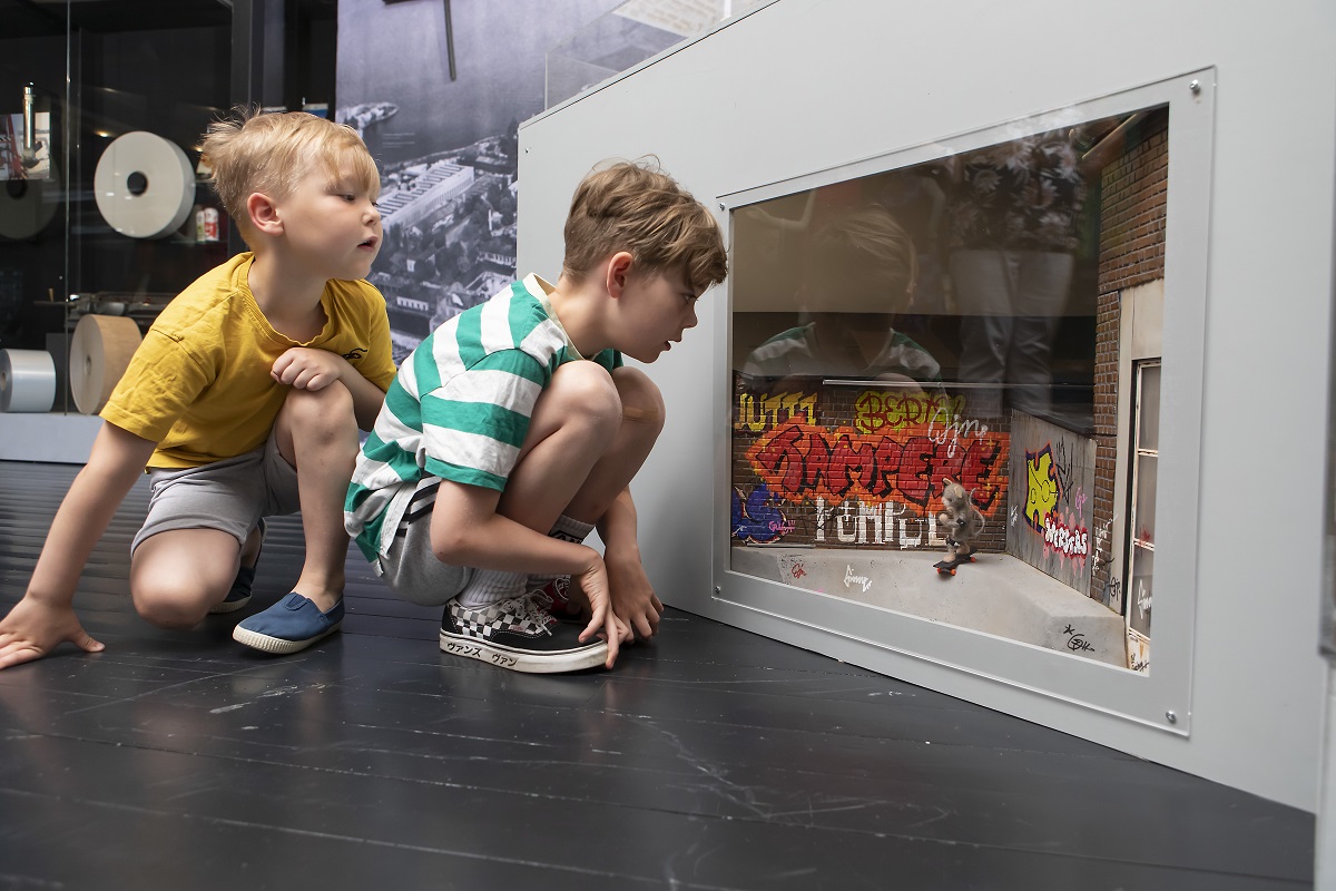 Kaksi lasta katselee pienoismallia, jossa hiiri skeittaa Hiedanrannassa.