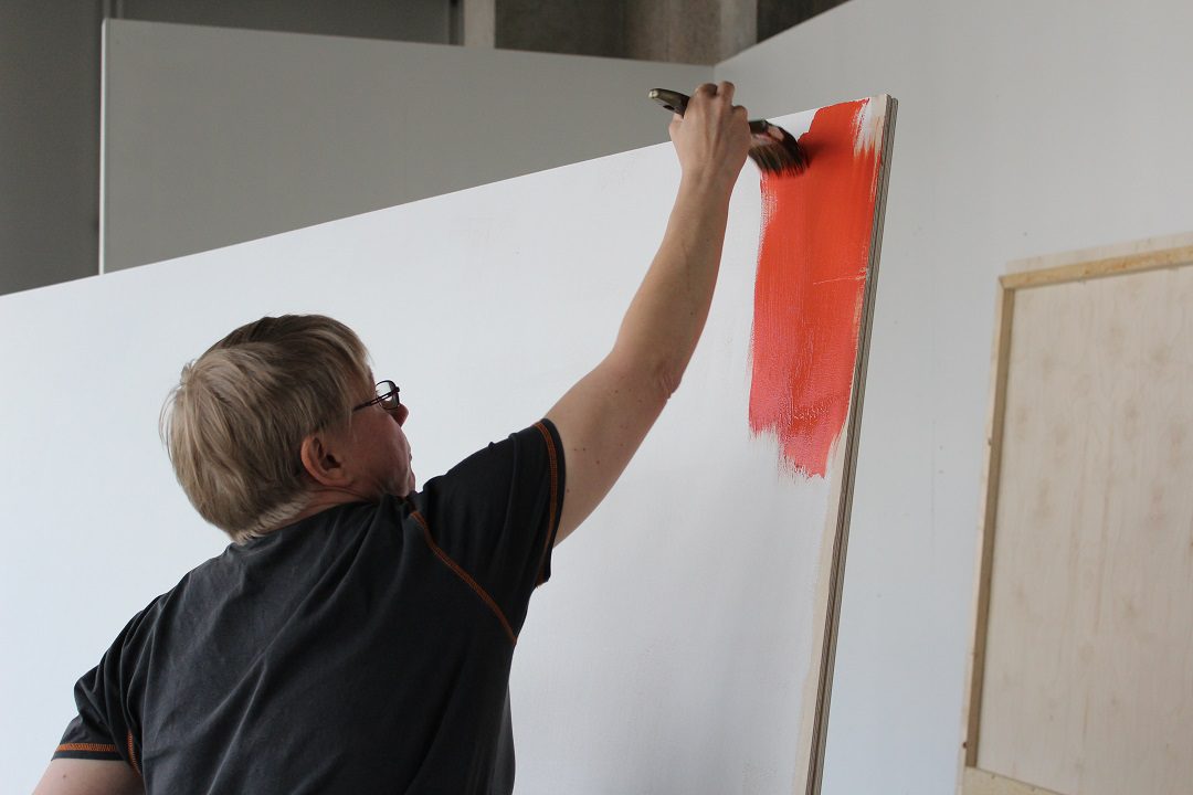 museosakki_Raini_Vallinharju_rakentaa_nayttelya_Werstas_web Nainen seisoo kynä kädessä fläppitaulun edessä ja katsoo kohti kameraa. Taululle on piirettynä erilaisia eläinhahmoja.