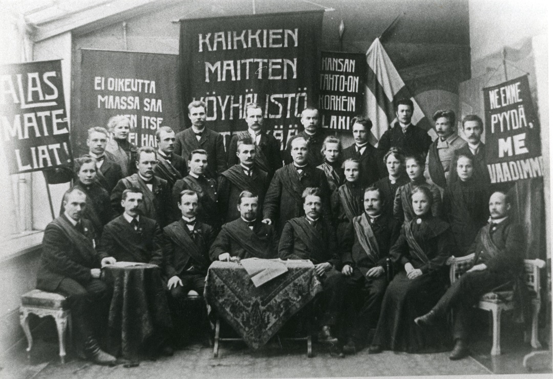 Joukko työmiehiä poseeraa lapioiden kanssa